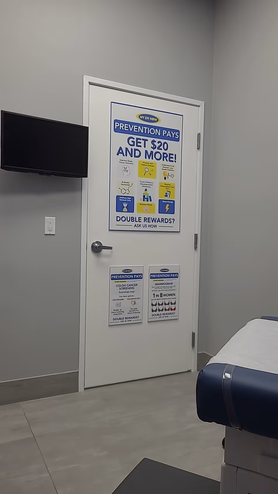 Interior clinic-like room with a door covered in health posters and a mounted TV