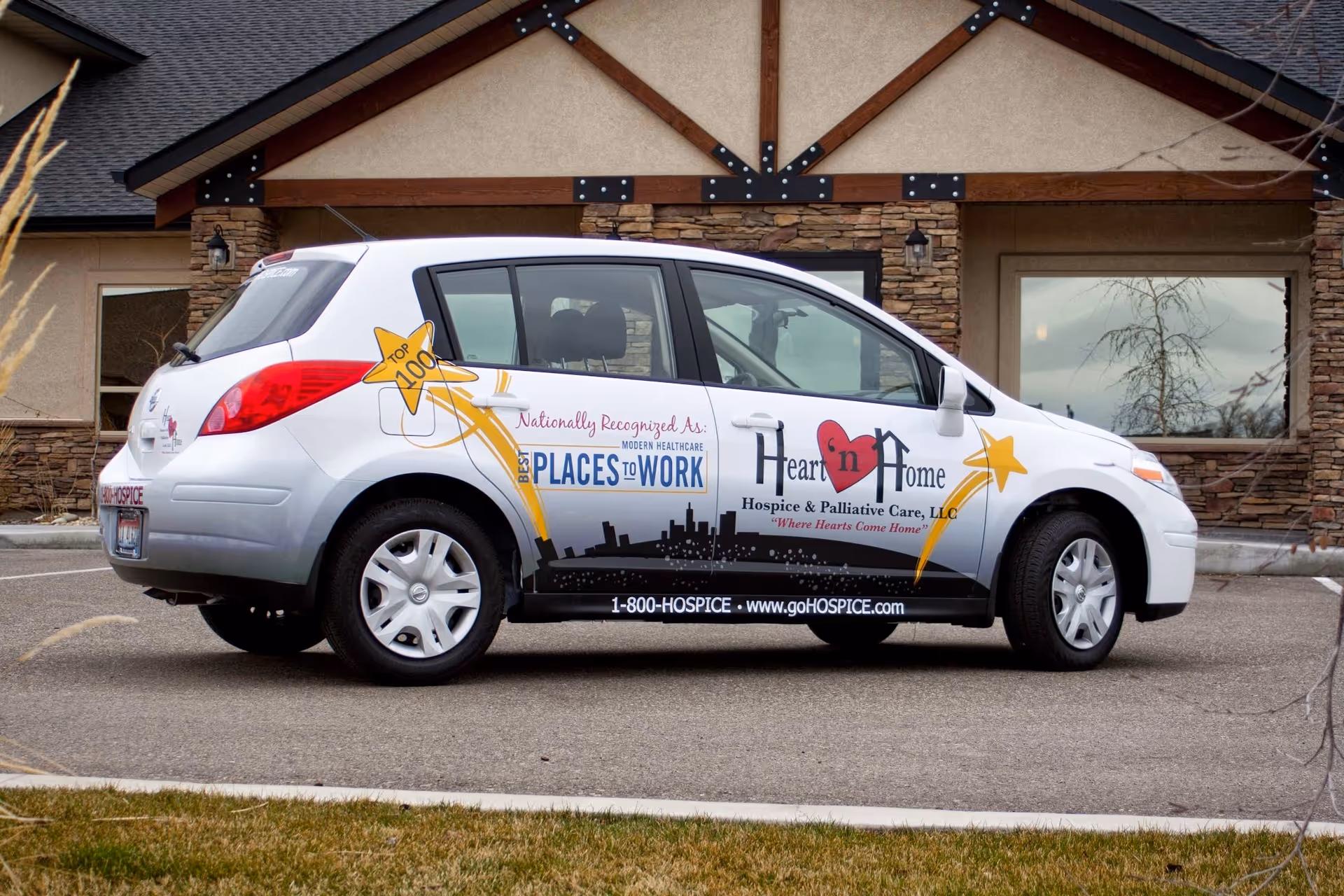 Branded Heart 'n Home Hospice van parked outside a stone building.