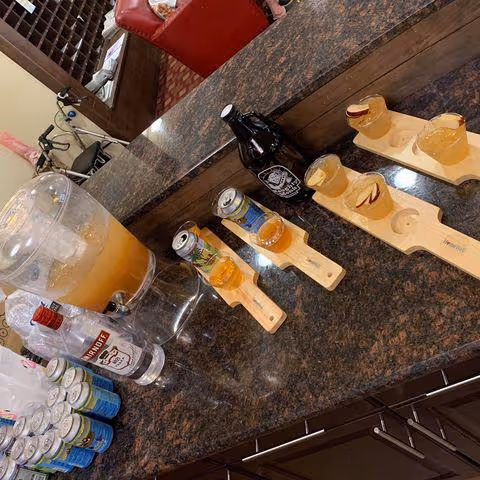 A granite counter displays beverage flights on wooden paddles with small glasses.
