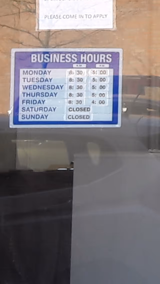 Blue business hours sign on glass door, reflecting interior seating.