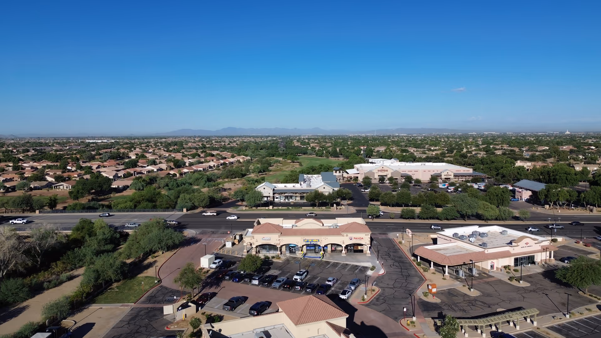 Aerial view of a suburban commercial complex with parking lots and surrounding neighborhoods.