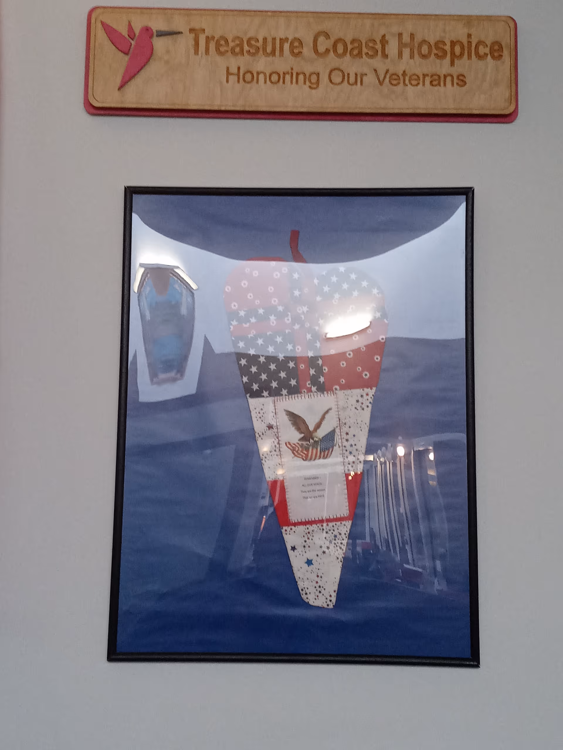 A Treasure Coast Hospice sign above a framed patriotic poster featuring an American flag rocket.