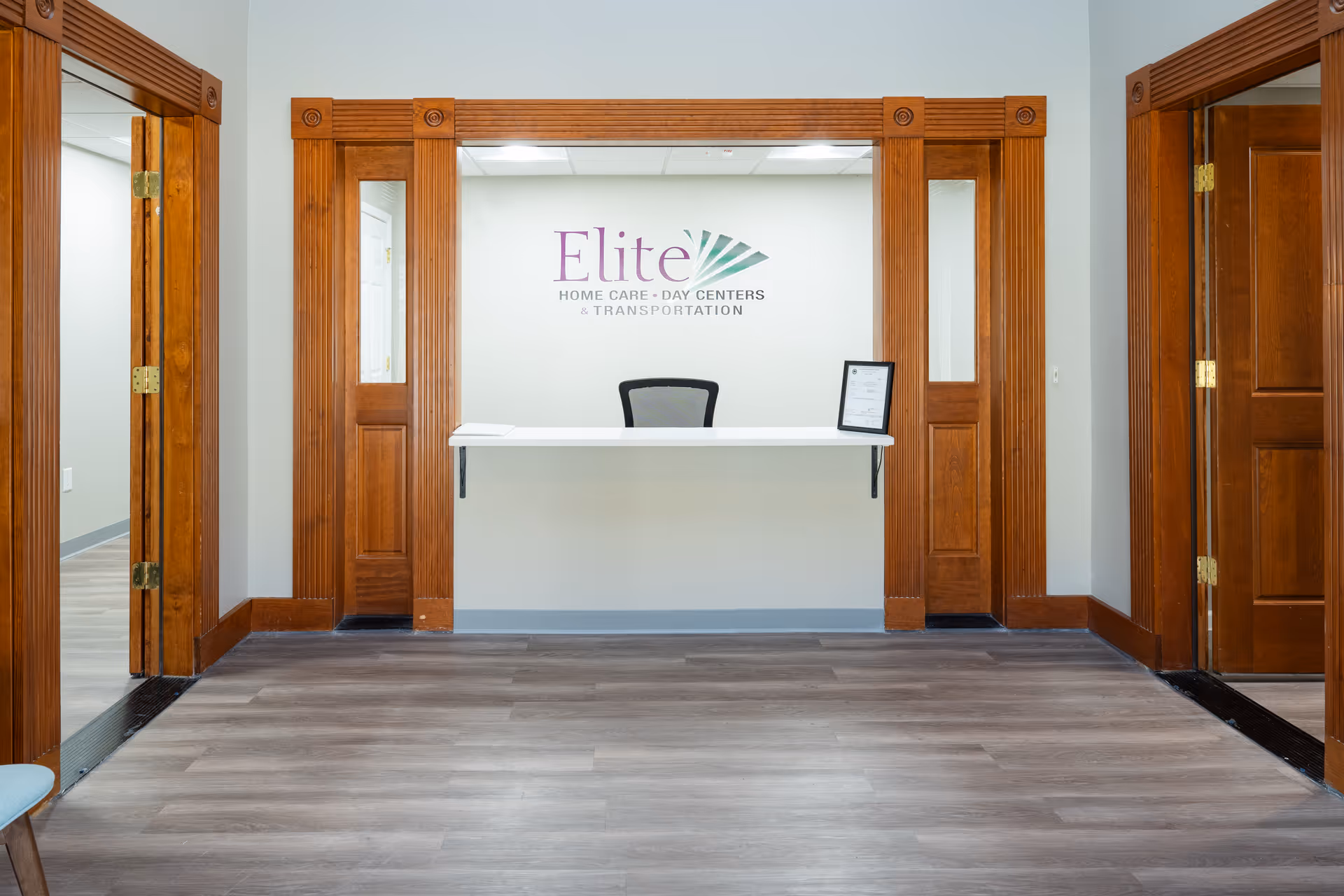 Reception desk centered between wooden door frames with Elite logo on the wall.