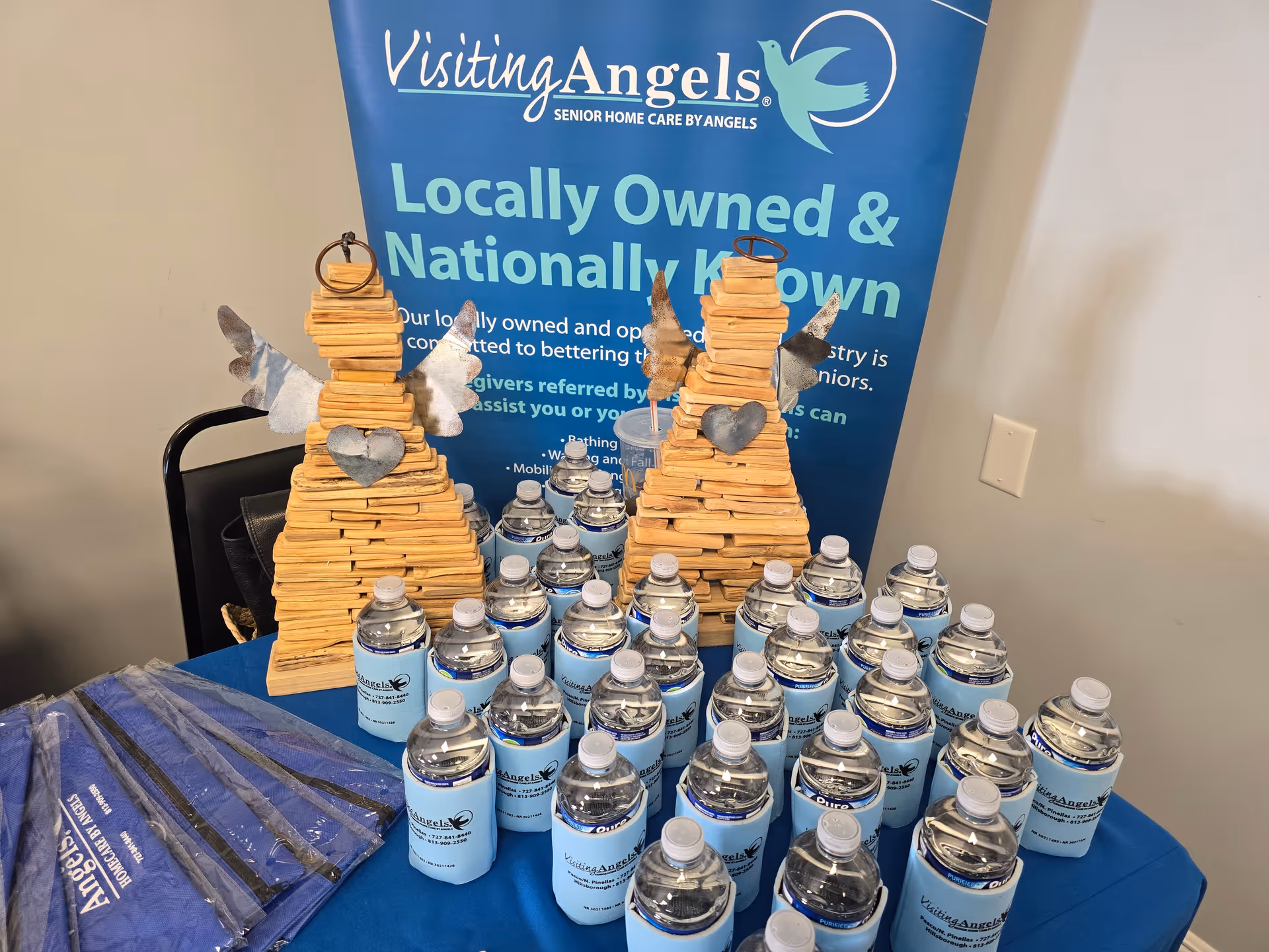 Promotional booth displays numerous water bottles and wooden sculptures in front of a blue banner.