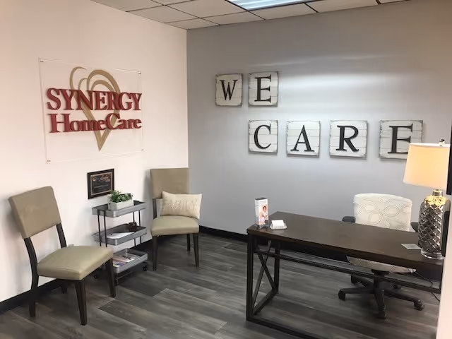 SYNERGY HomeCare lobby area with desk, chairs, and 'We Care' decor.