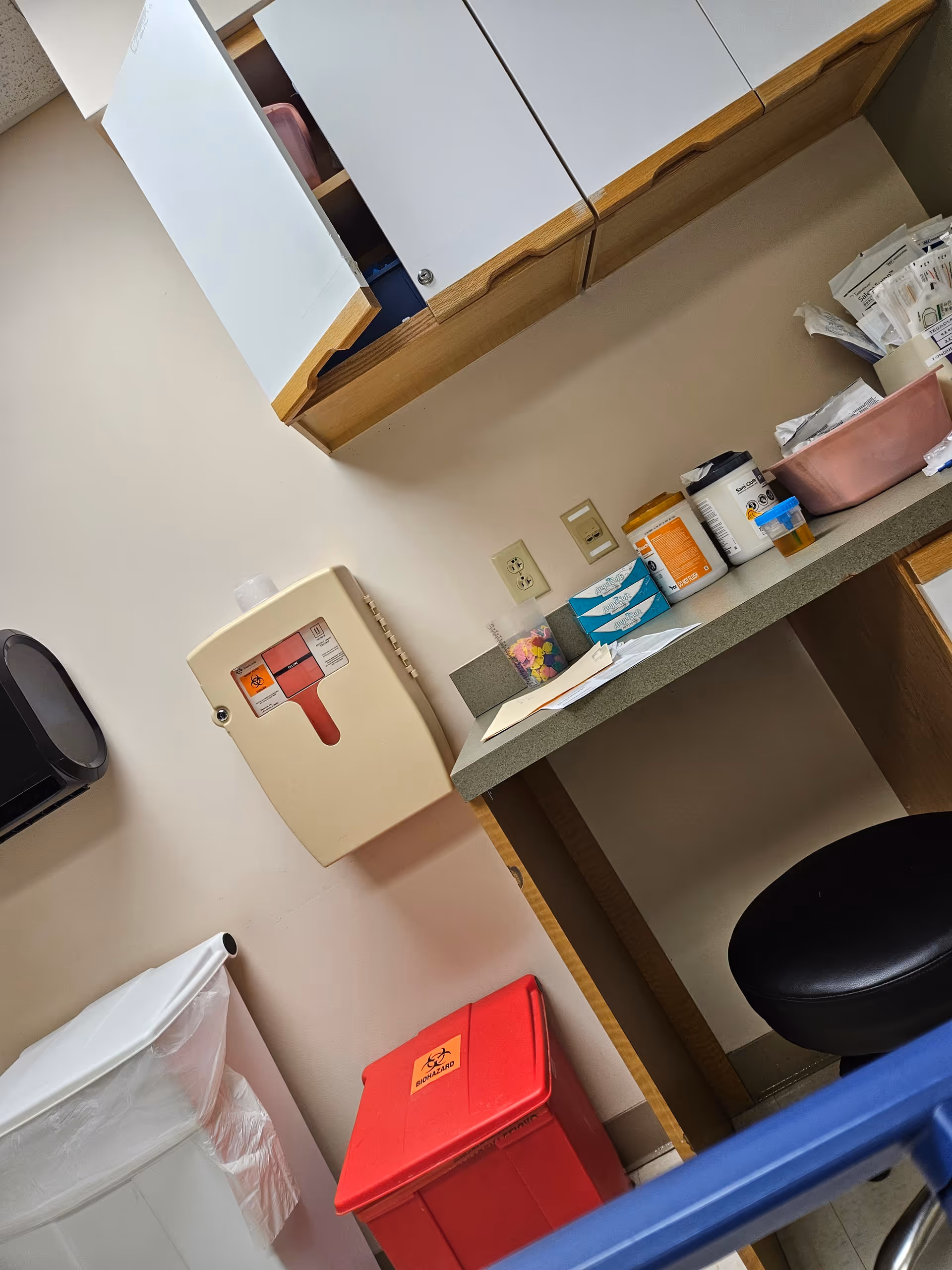 Clinical supply area with cabinets, a sharps container, and disposal bins.
