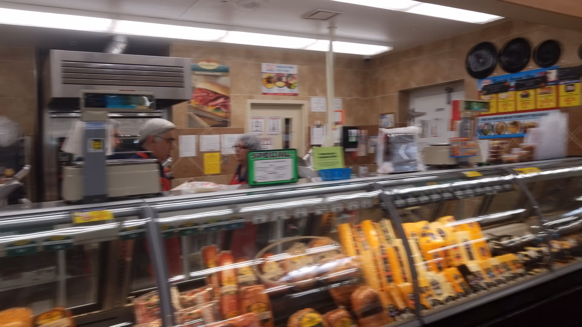 Deli counter inside Discount Drug Mart with two staff behind the glass display.