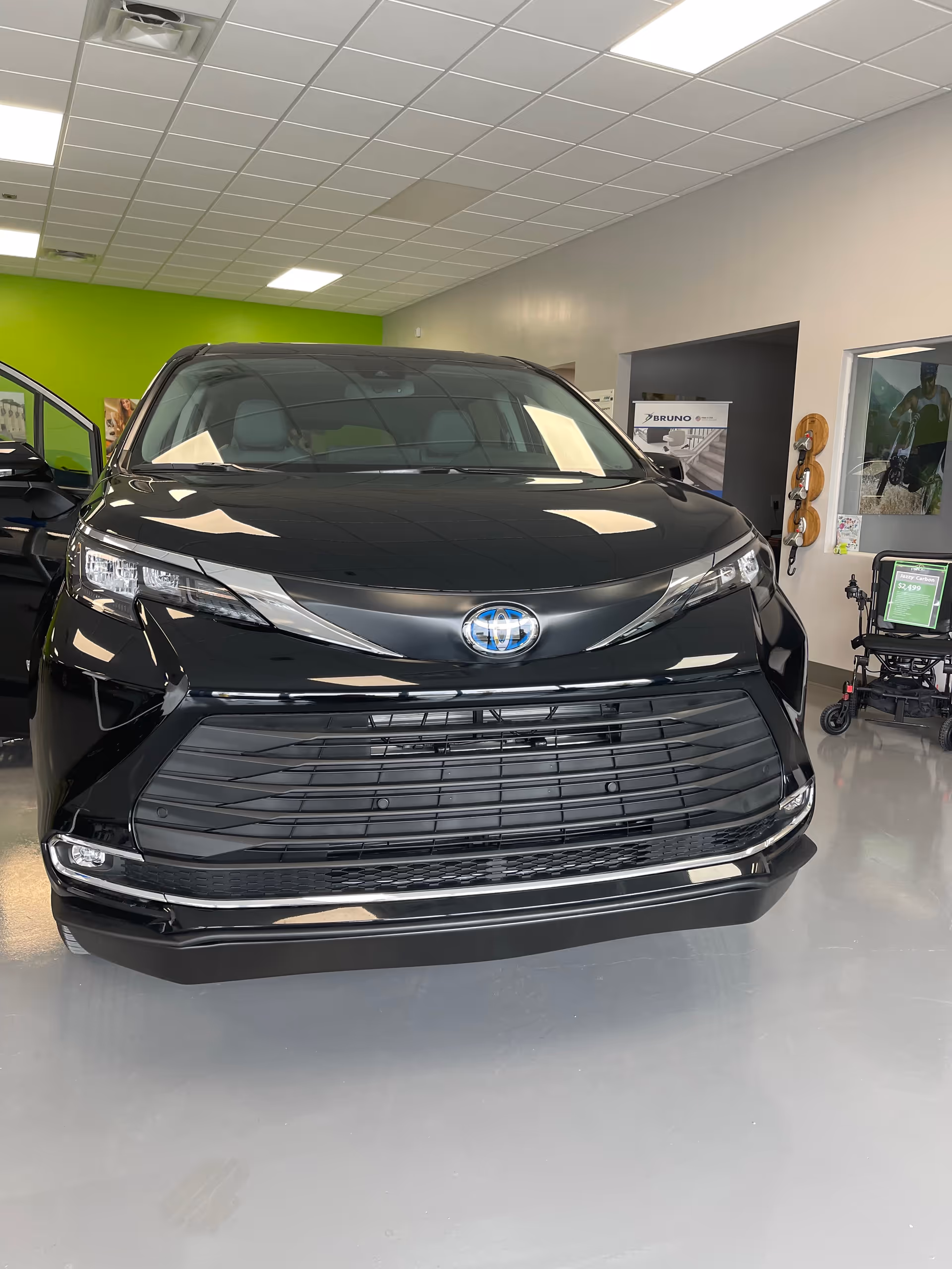 Black Toyota SUV displayed inside MobilityWorks showroom with bright lights and lime green wall.