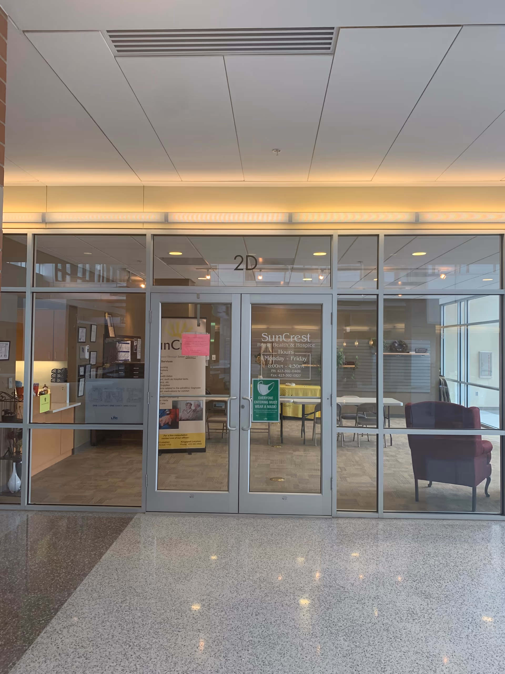 Glass entrance doors labeled 2D open into a SunCrest Hospice lobby.