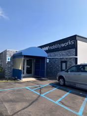 Exterior view of MobilityWorks building with blue entrance canopy and handicap parking.
