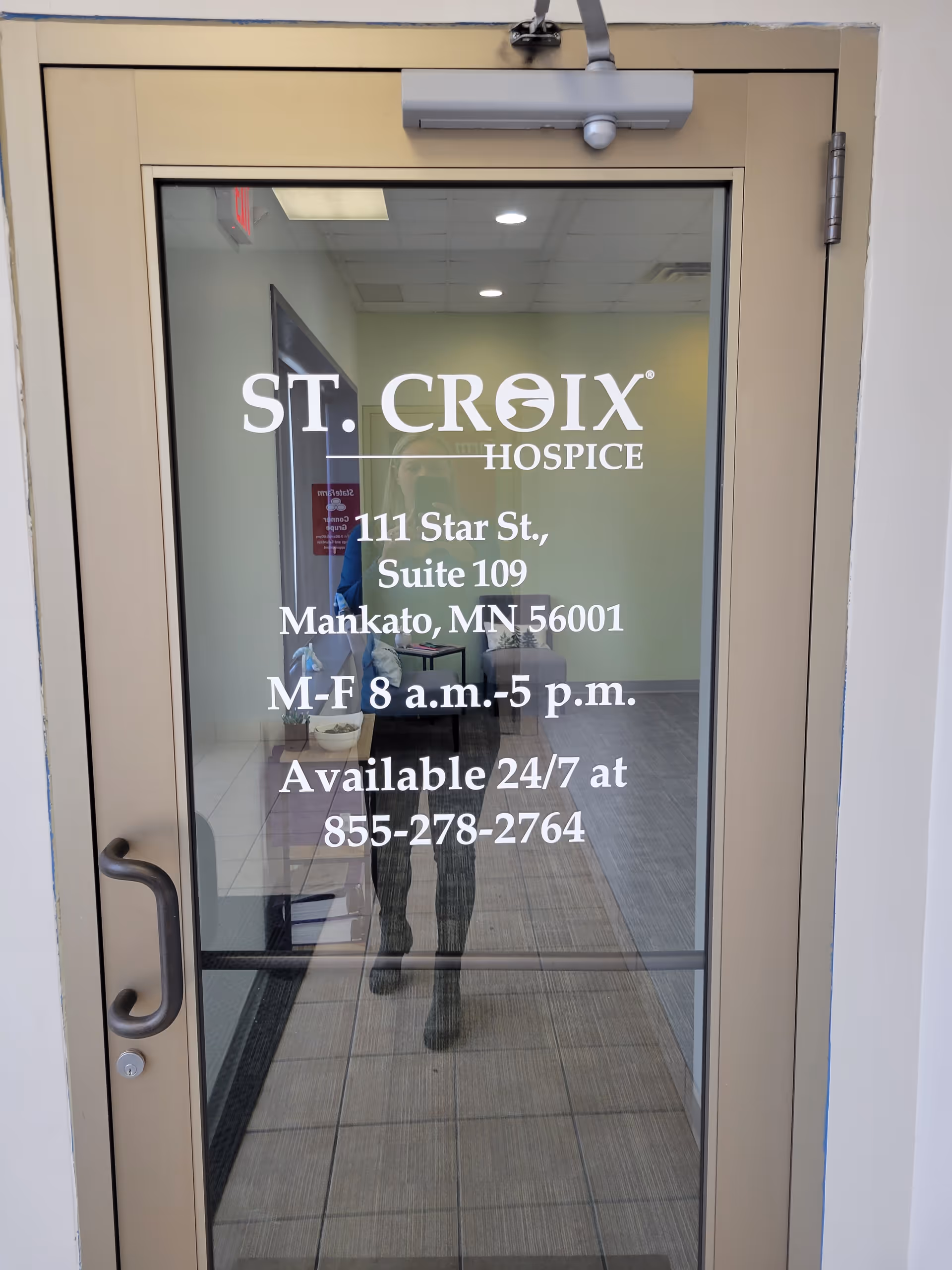 Glass entry door displaying St. Croix Hospice sign and address in a lobby.