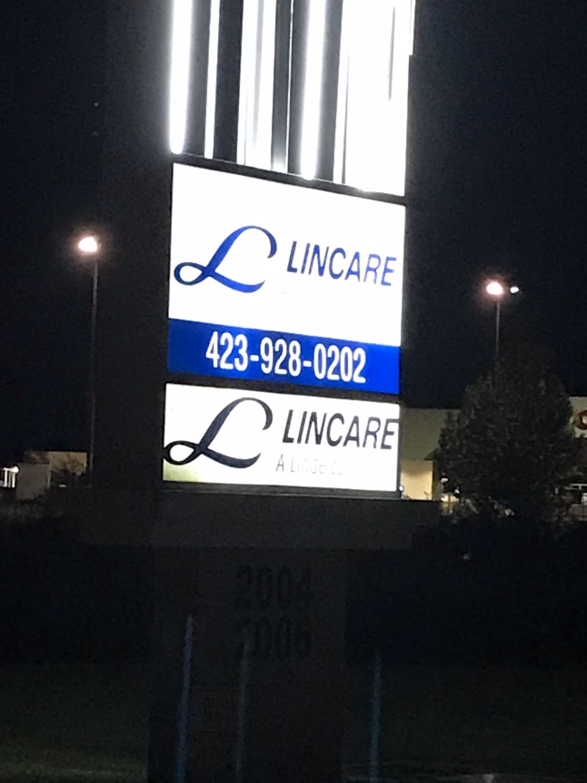 Nighttime view of a lit LINCARE sign on the building front.