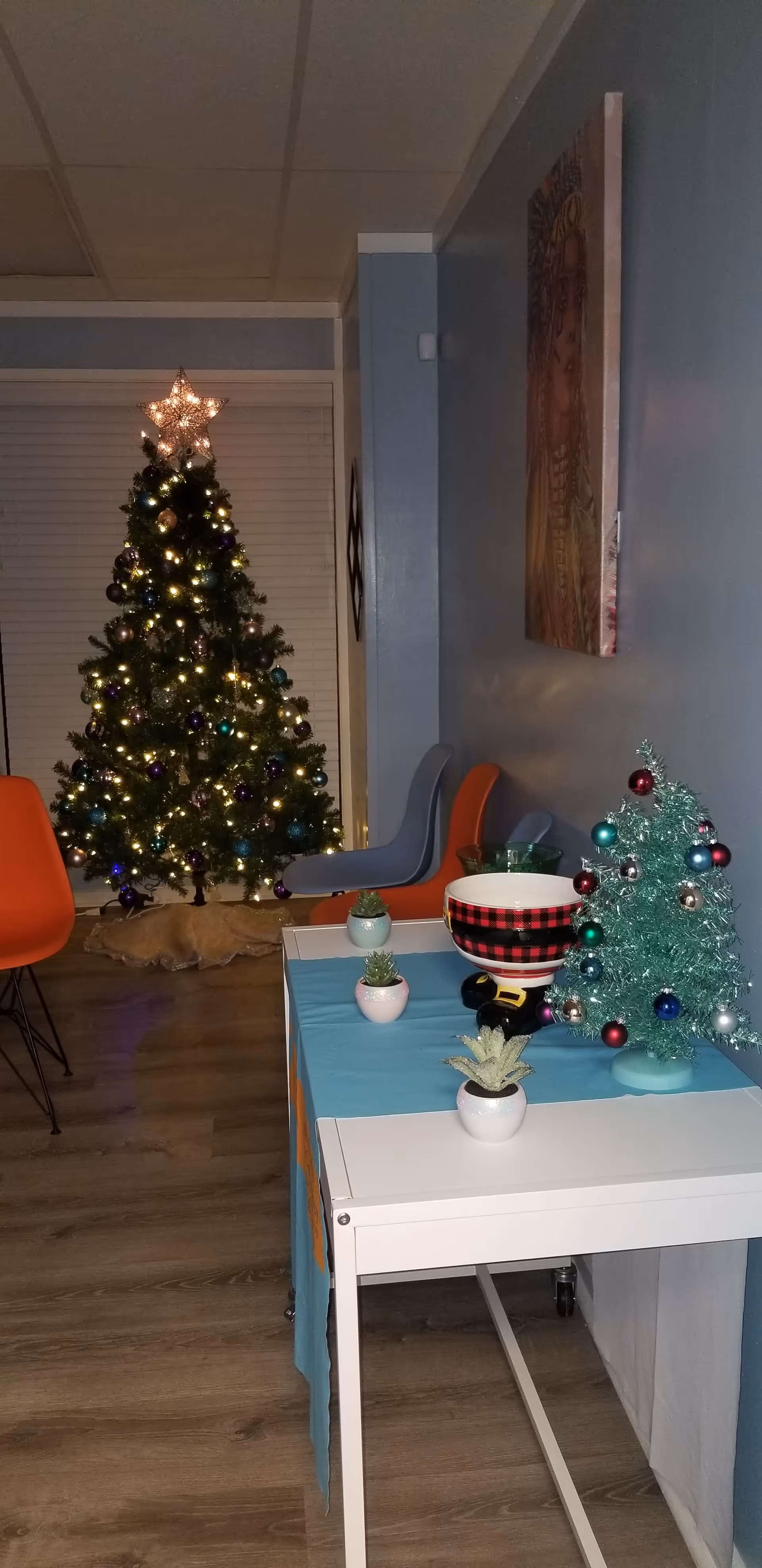 Decorated Christmas tree and small ornaments adorn a facility's cozy living room with chairs.