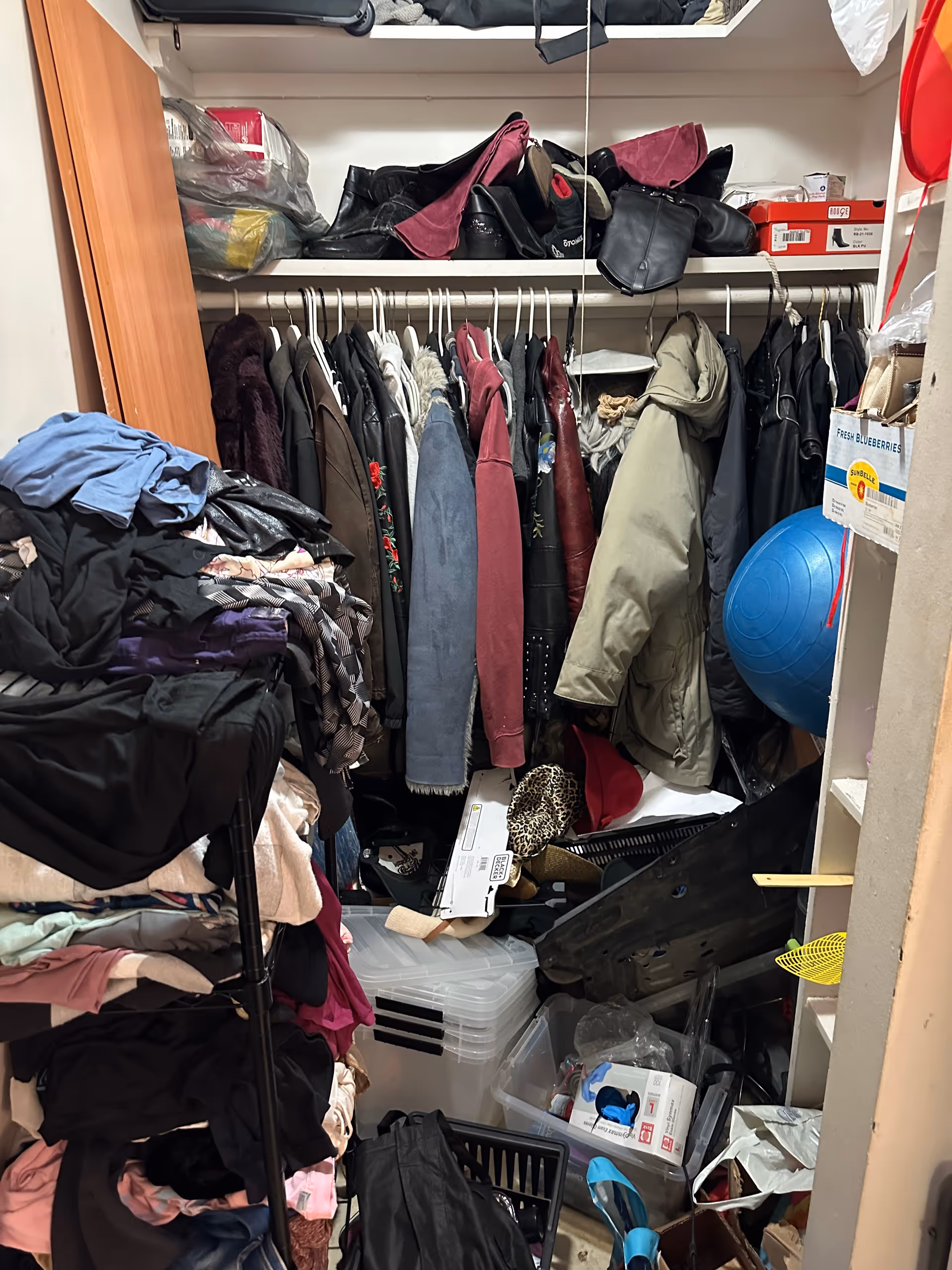Cluttered closet in a senior living facility with coats, bags, and assorted items