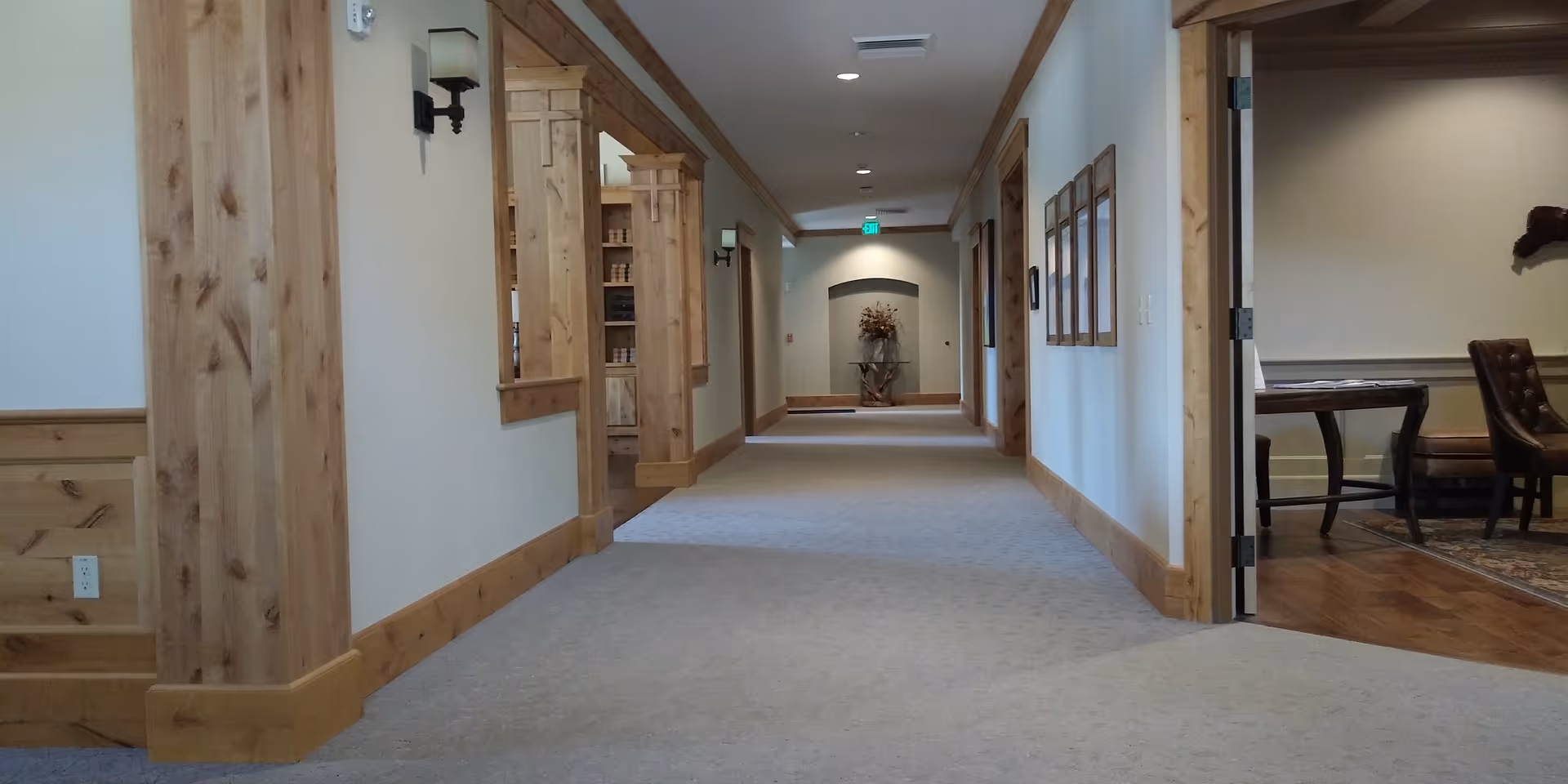 Long well-lit hallway inside Pete Moore Hospice House with wooden trim and a sitting room visible.
