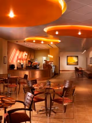 Indoor dining area at Longhorn Village with round tables and a curved service counter.
