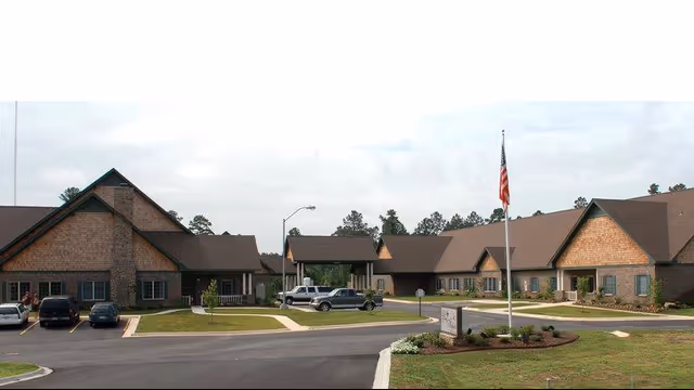 Exterior view of Life Touch Hospice facility with brick buildings, parking, and a flagpole