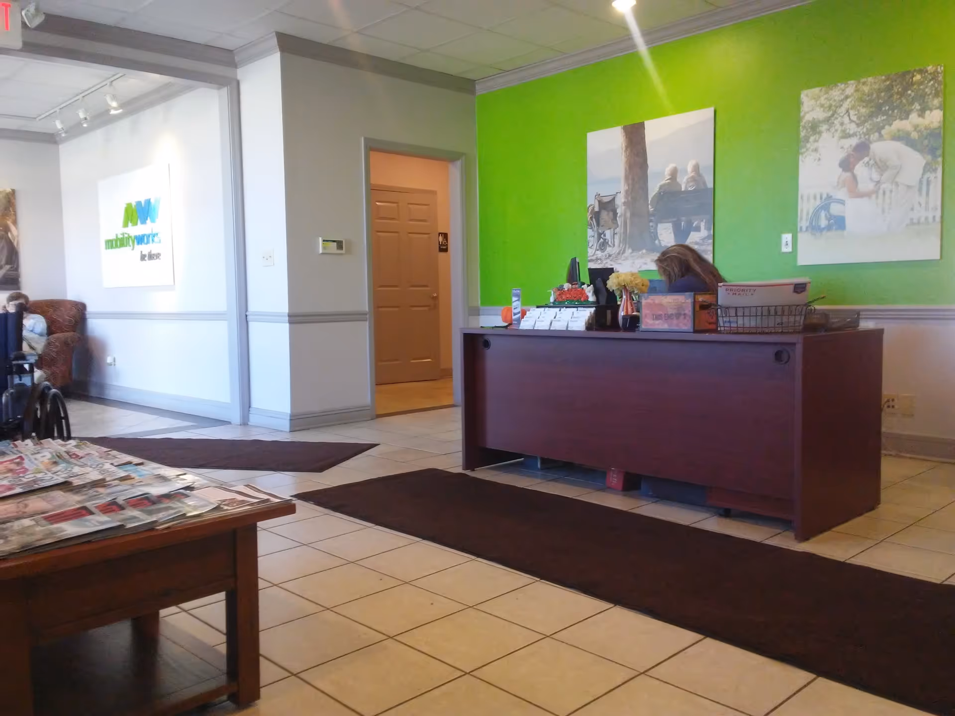 Lobby reception area with a dark desk, green wall, and visitor seating.