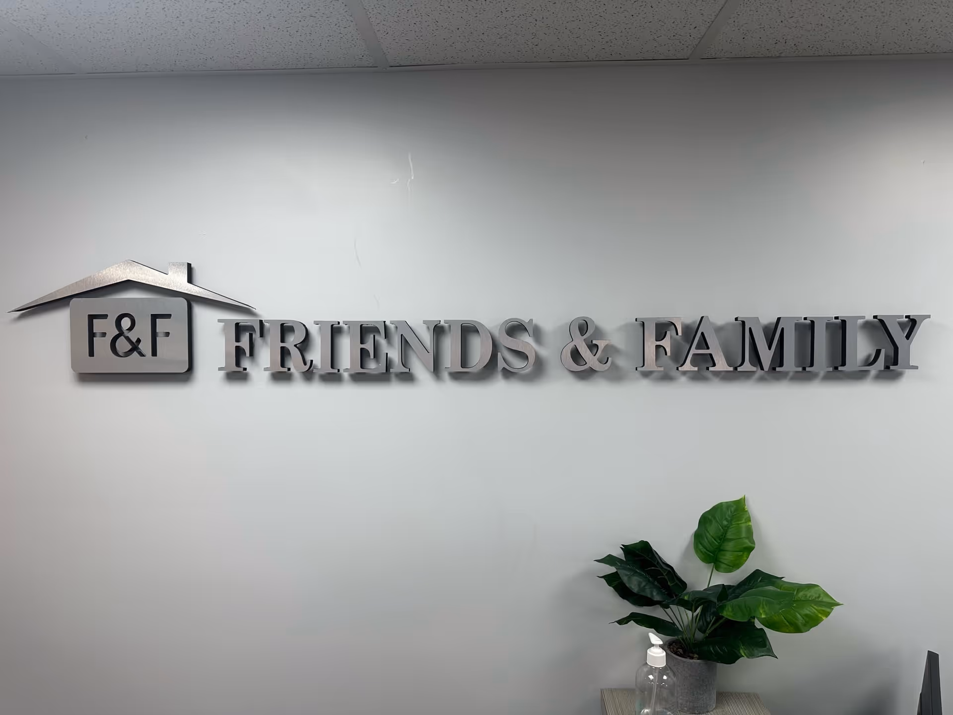 Interior wall featuring a metal Friends & Family sign and a potted plant.