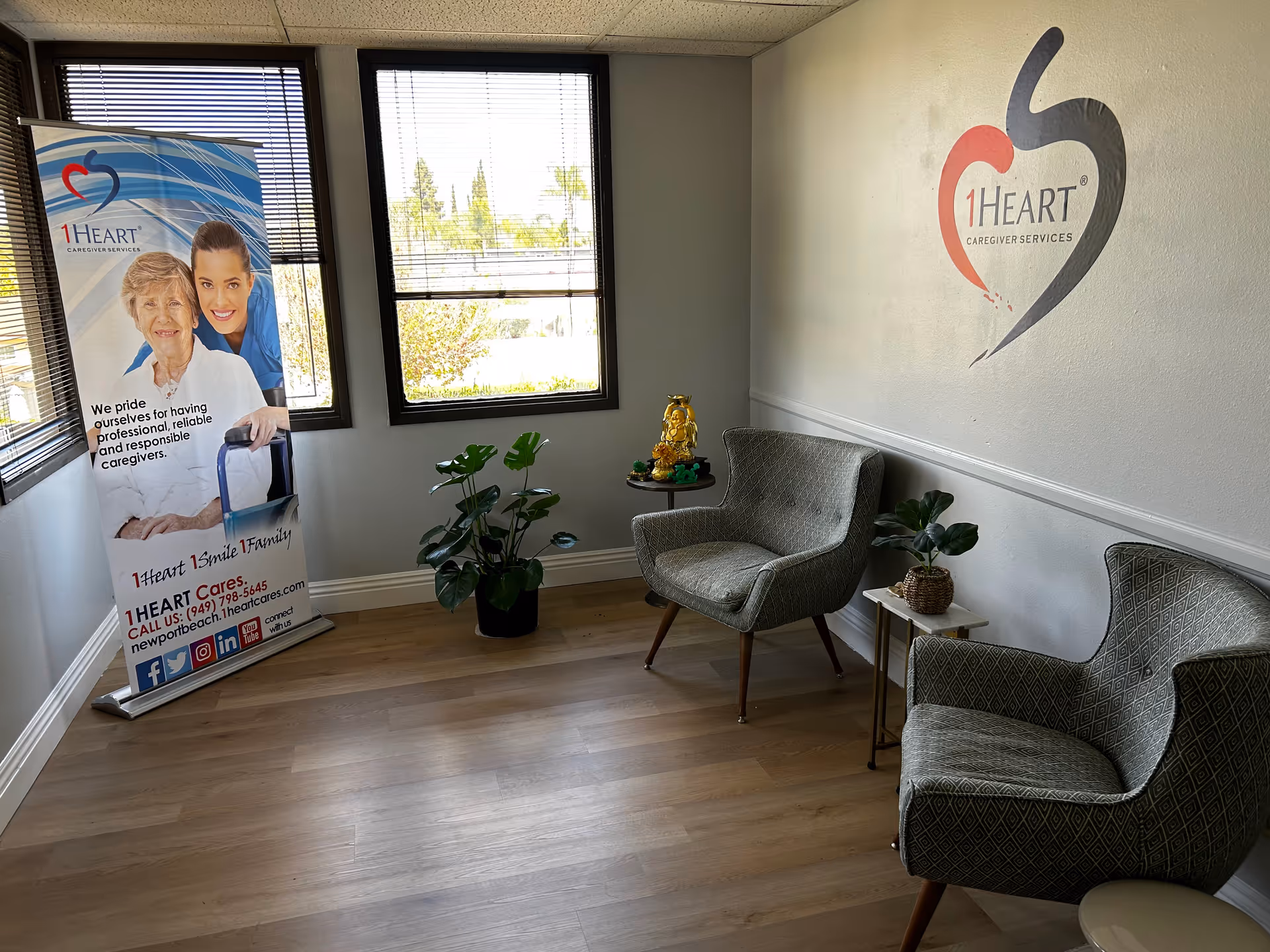 Interior waiting area with two chairs, plants, and a 1Heart banner.