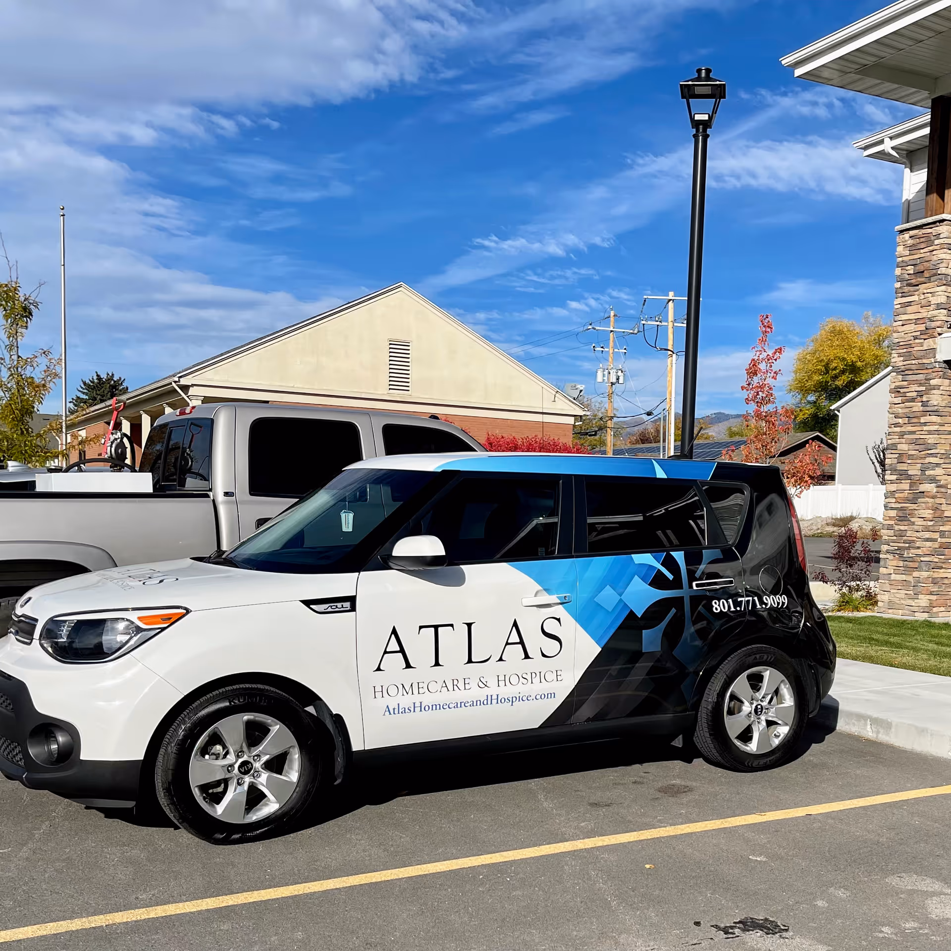 Atlas Homecare and Hospice branded van parked in a lot beside a stone-faced building.