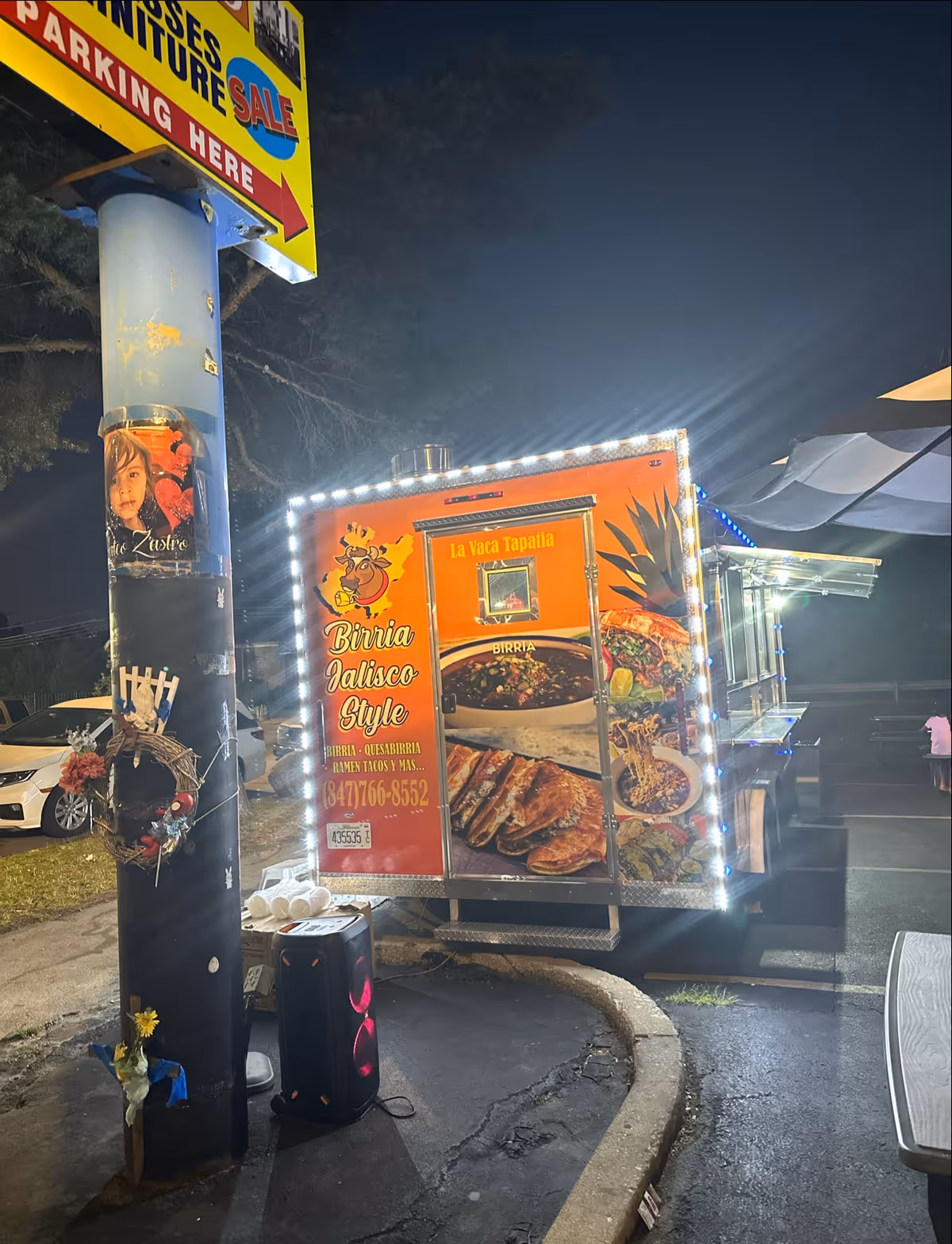 Nighttime outdoor food truck with illuminated edges and a colorful menu display.