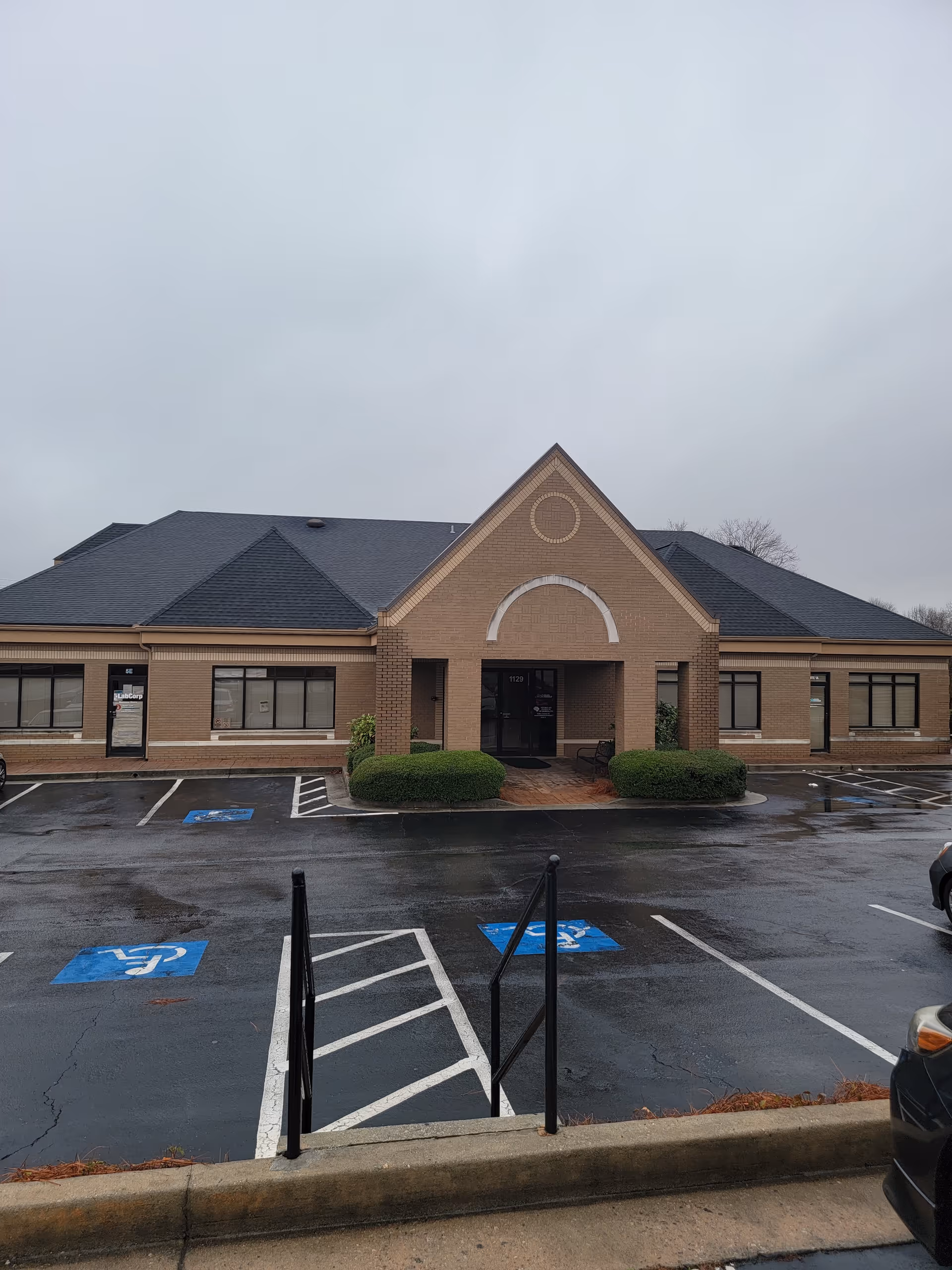 Exterior view of a brick senior care building with a parking lot and accessible entrance.