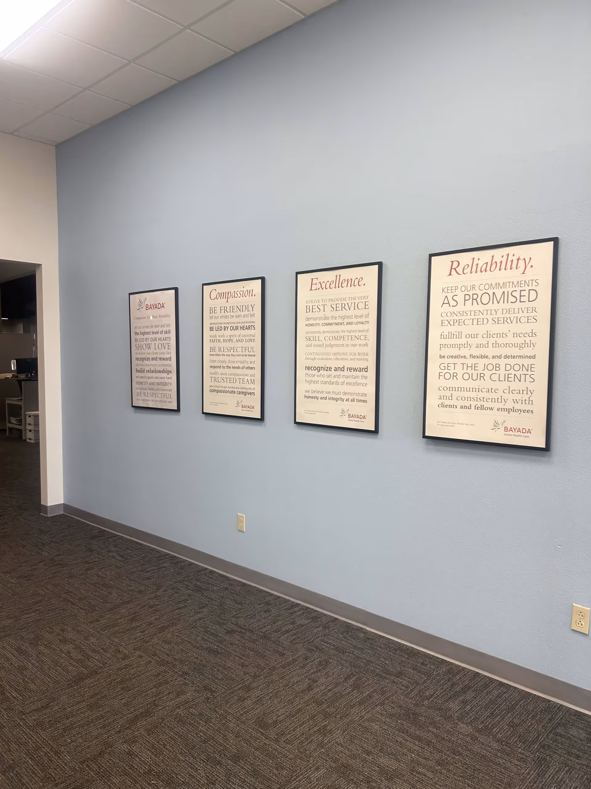 Interior hallway with five framed posters along a light blue wall.