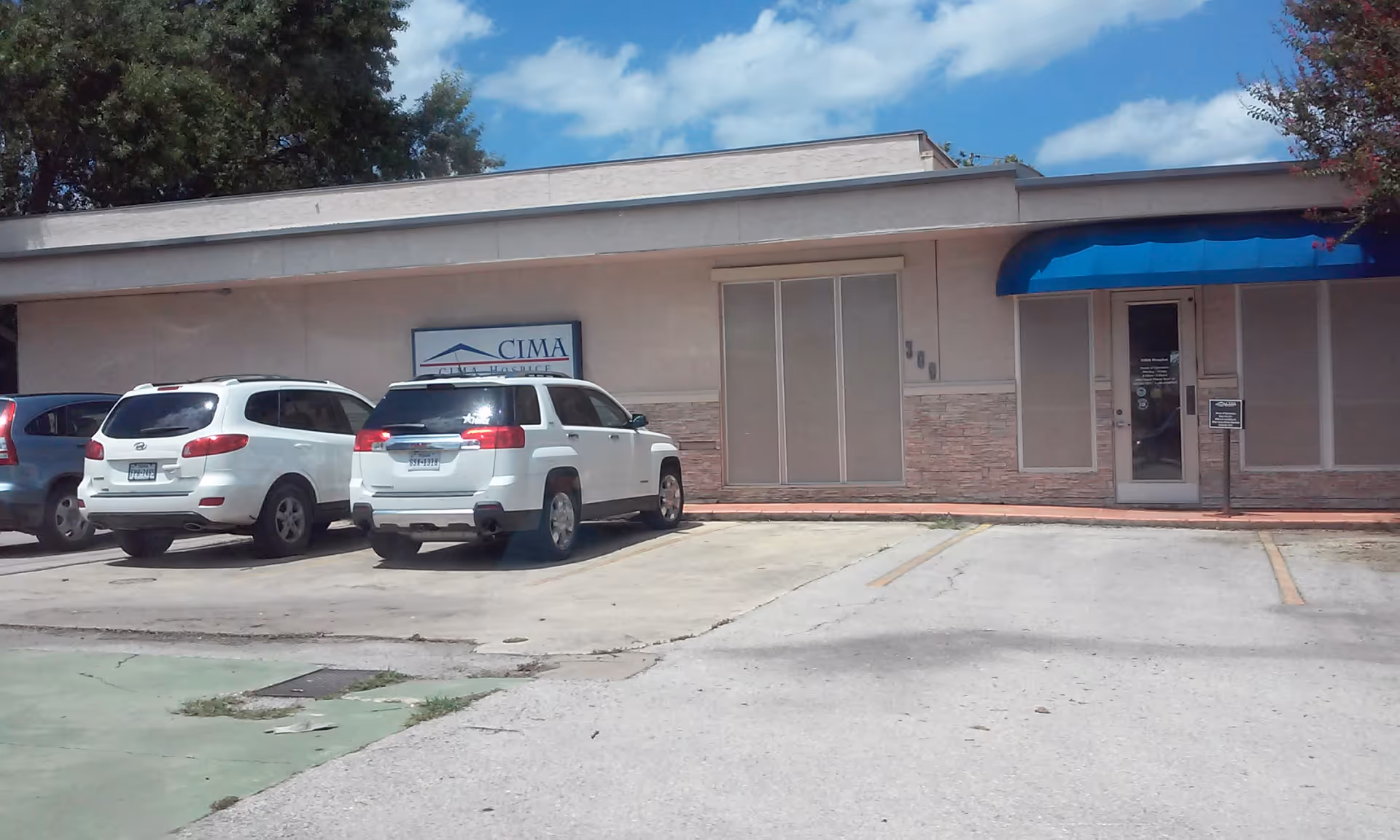 Exterior of Elara Caring facility with parking lot and blue awning entrance.
