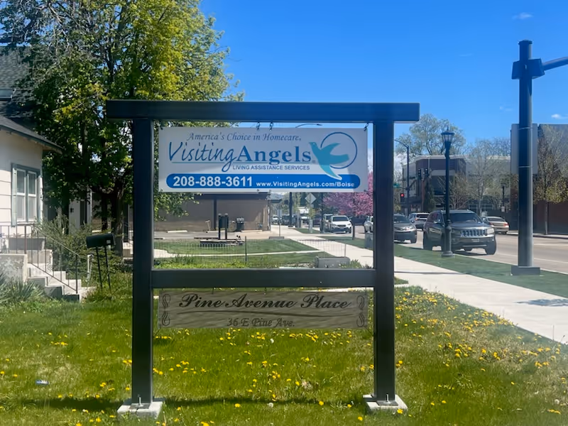 Outdoor Visiting Angels sign on a framed display by the sidewalk and street.