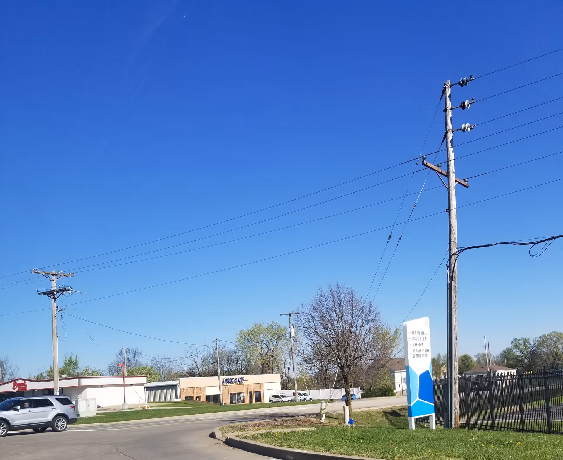 Blue sky above a LINCARE facility exterior with parking and power lines.