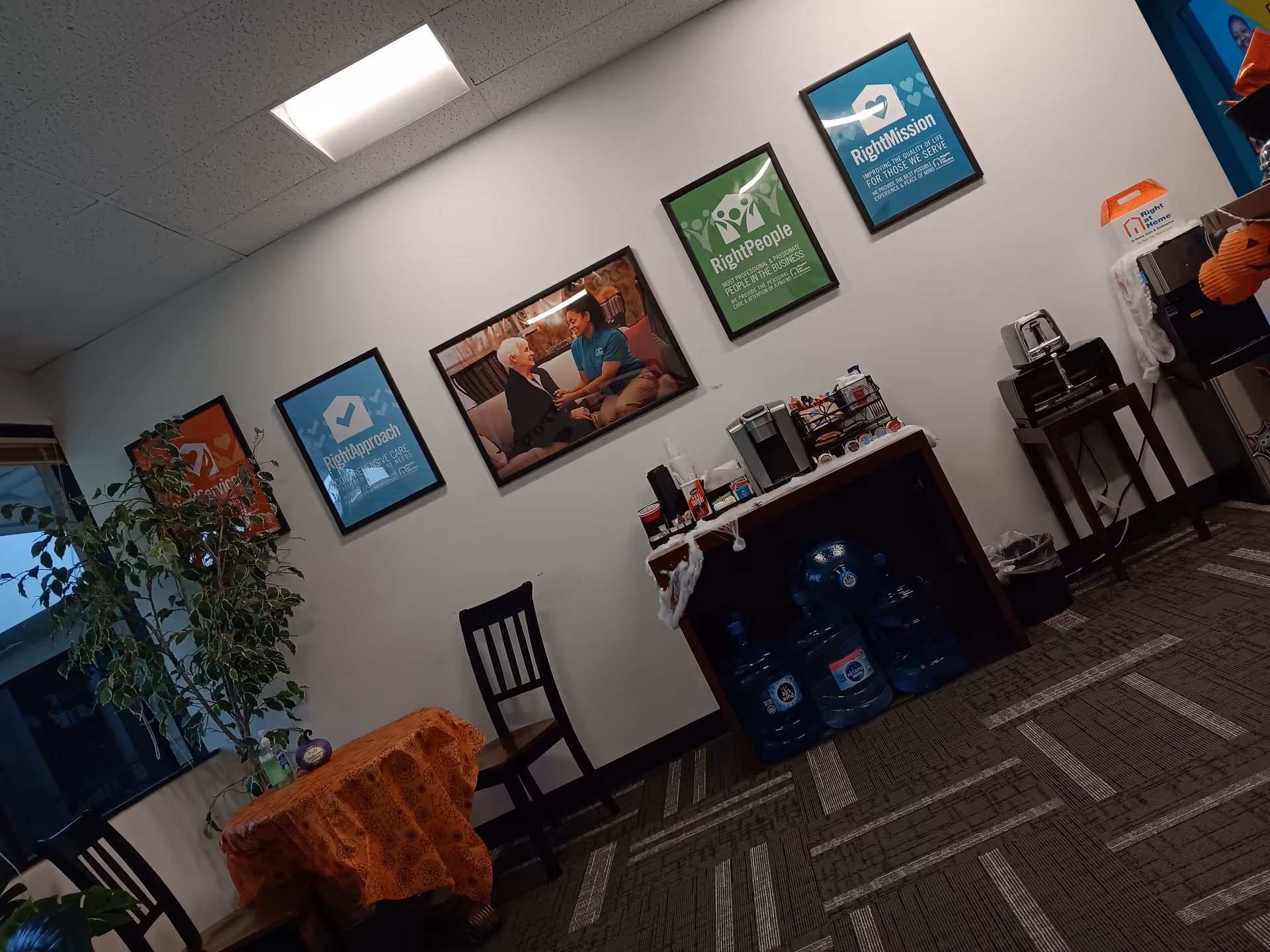 Interior common area with Right at Home posters and a coffee station.
