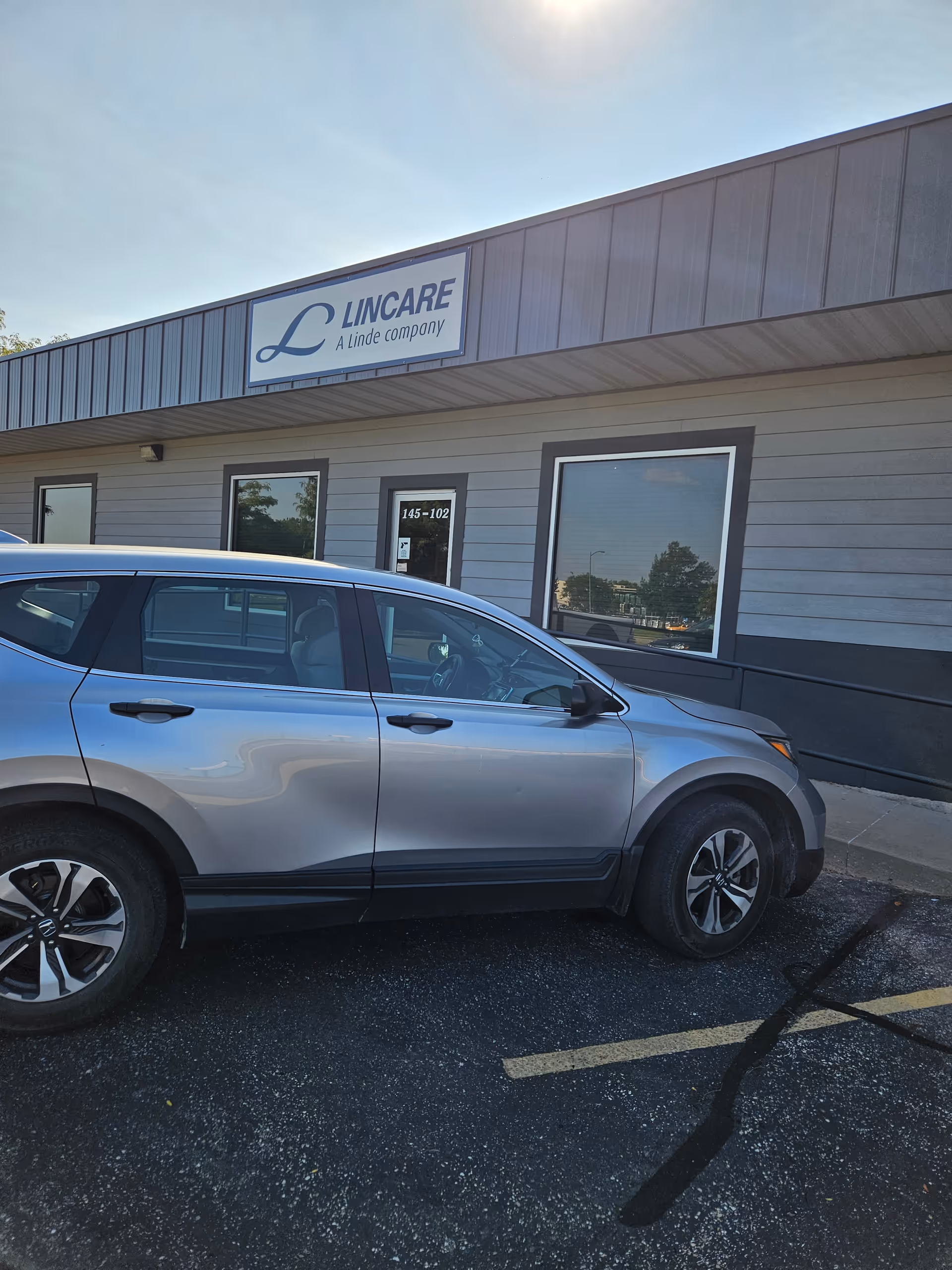 Exterior of LINCARE facility with sign and gray SUV parked in front
