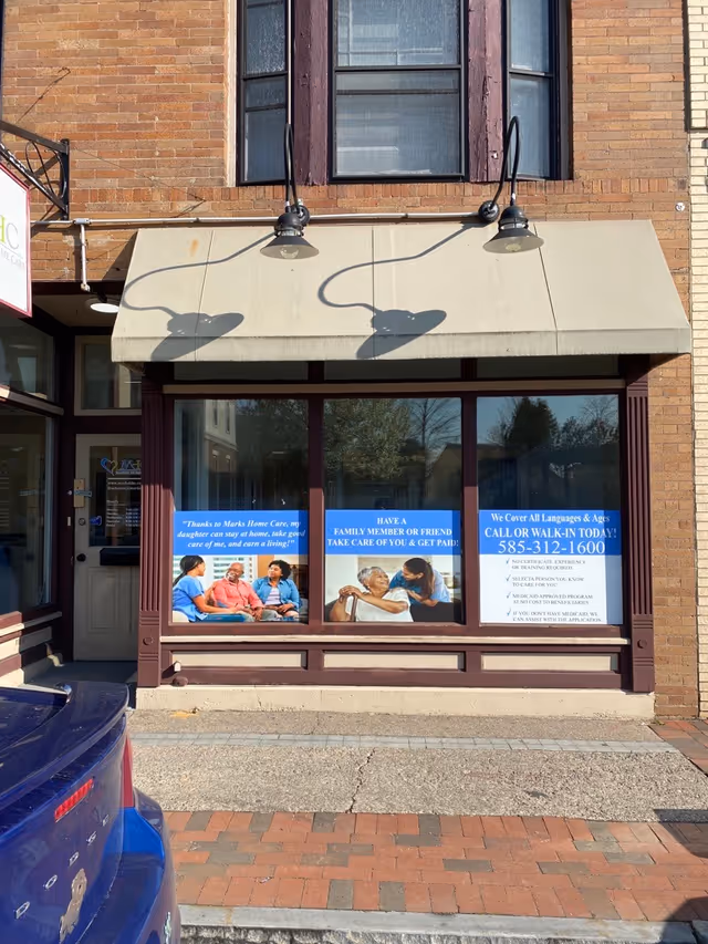 Facade of a brick building with a glass storefront and posters.