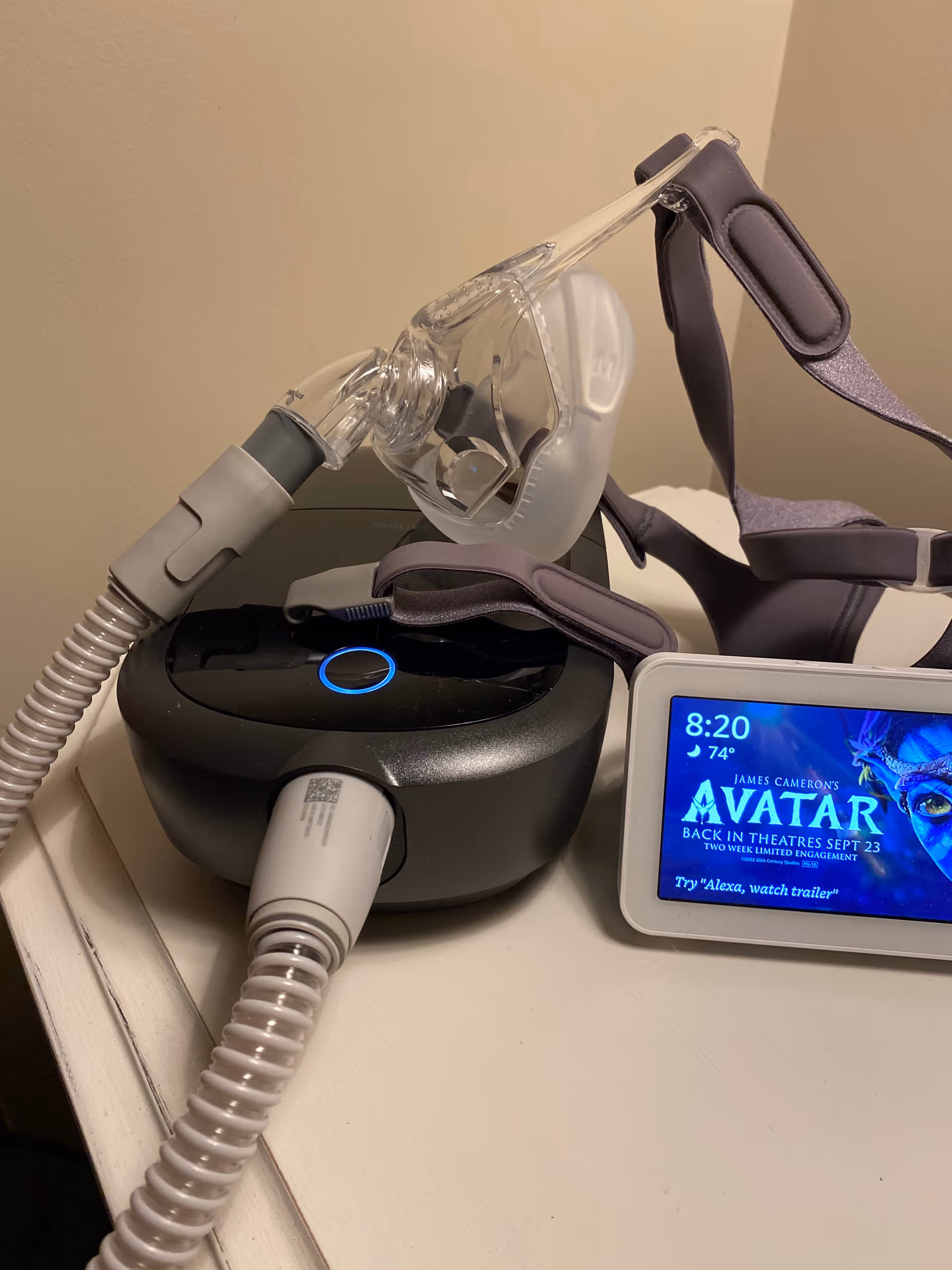 Close up of a CPAP machine with mask and tubing on a bedside table
