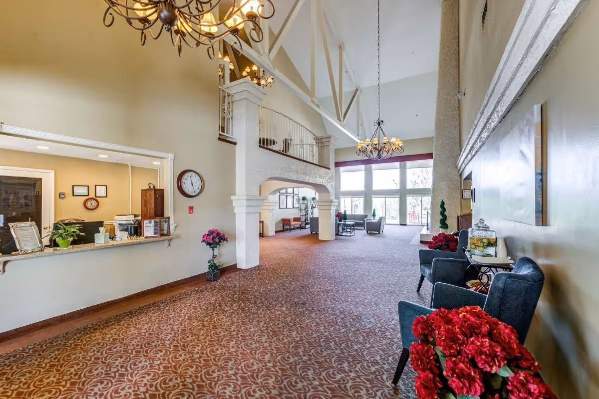 Spacious lobby with reception desk, seating, chandeliers, and large windows.