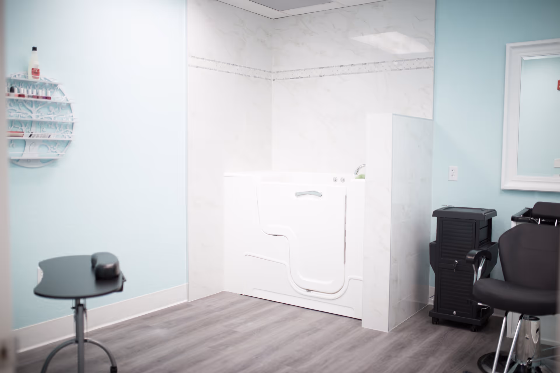 Salon area with teal walls, a white appliance, mirror, and black styling chair.