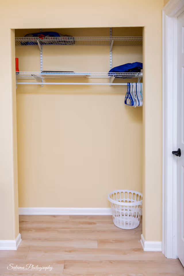 Open closet with wire shelves, hanging rod, and a white laundry basket.