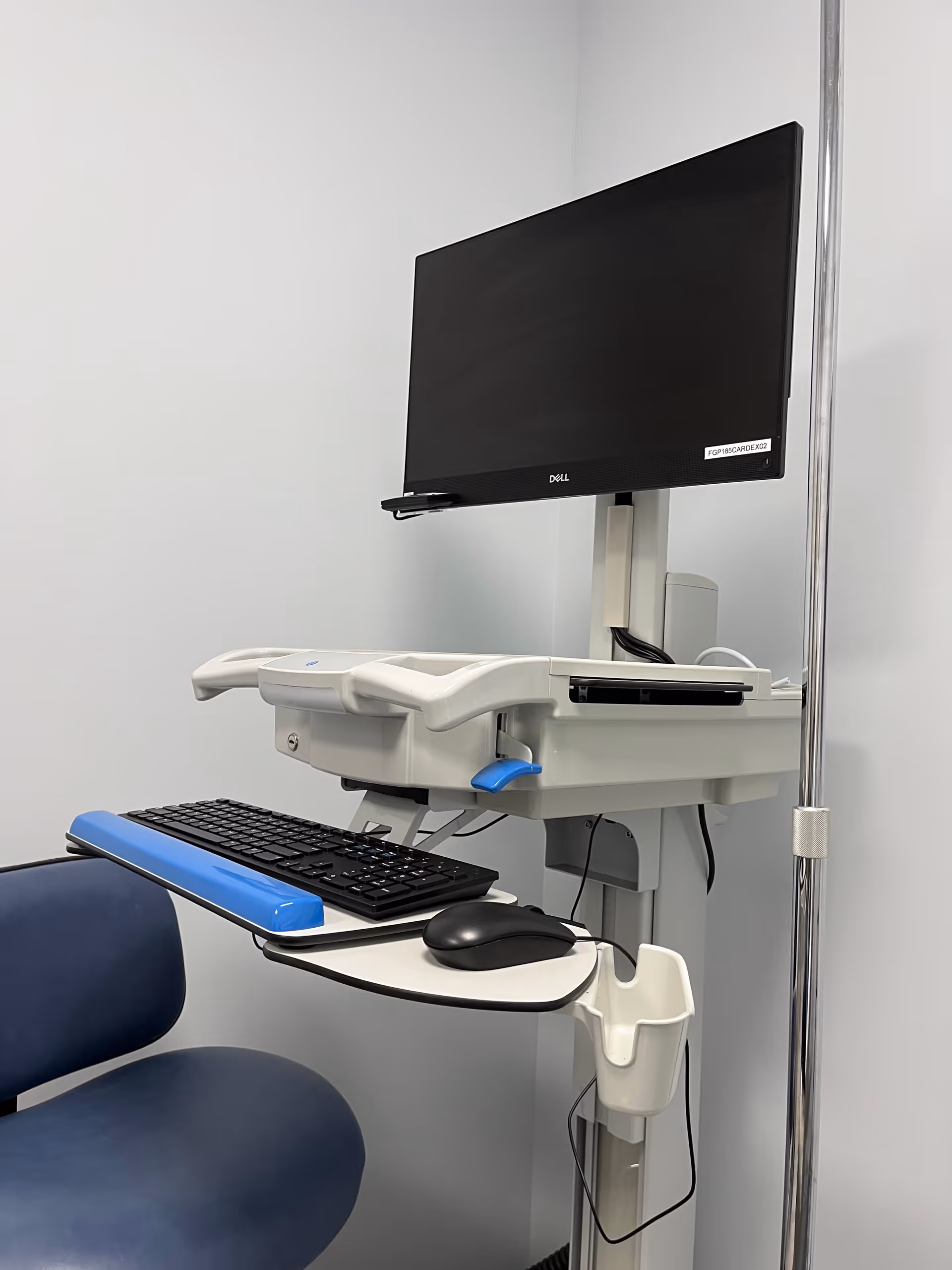 Clinical computer workstation with monitor, keyboard, and mouse in an exam room