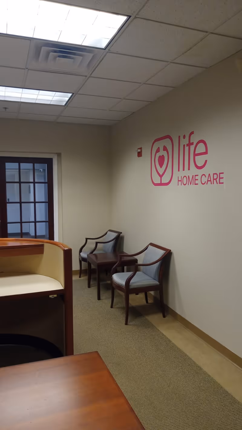 Interior hallway with a reception desk, waiting chairs, and Life Home Care logo on wall.