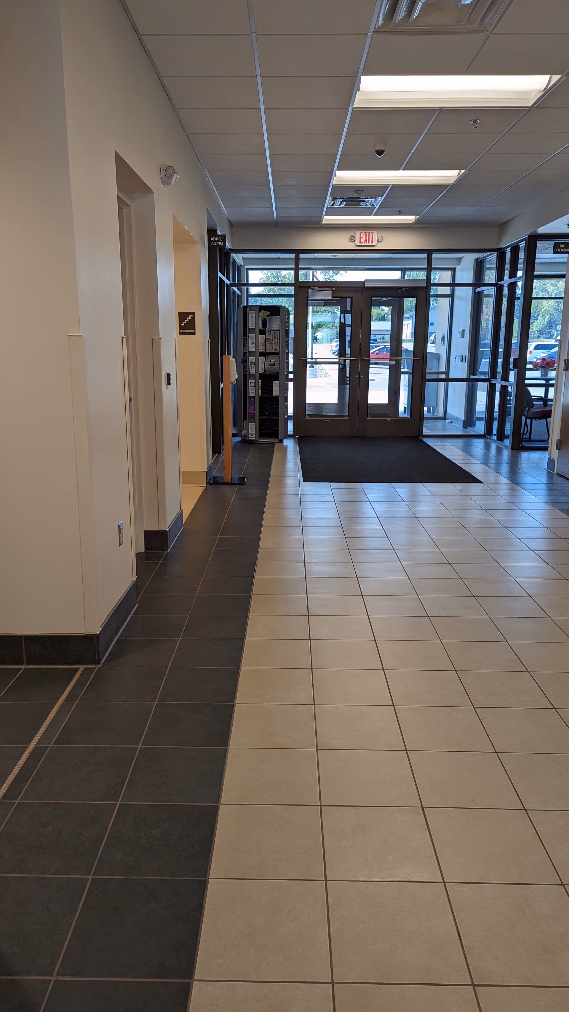 Interior senior living facility lobby with tiled floor, glass doors, and natural light.