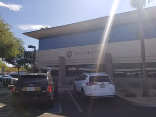 Front exterior of a building with parked cars and an Encompass sign.