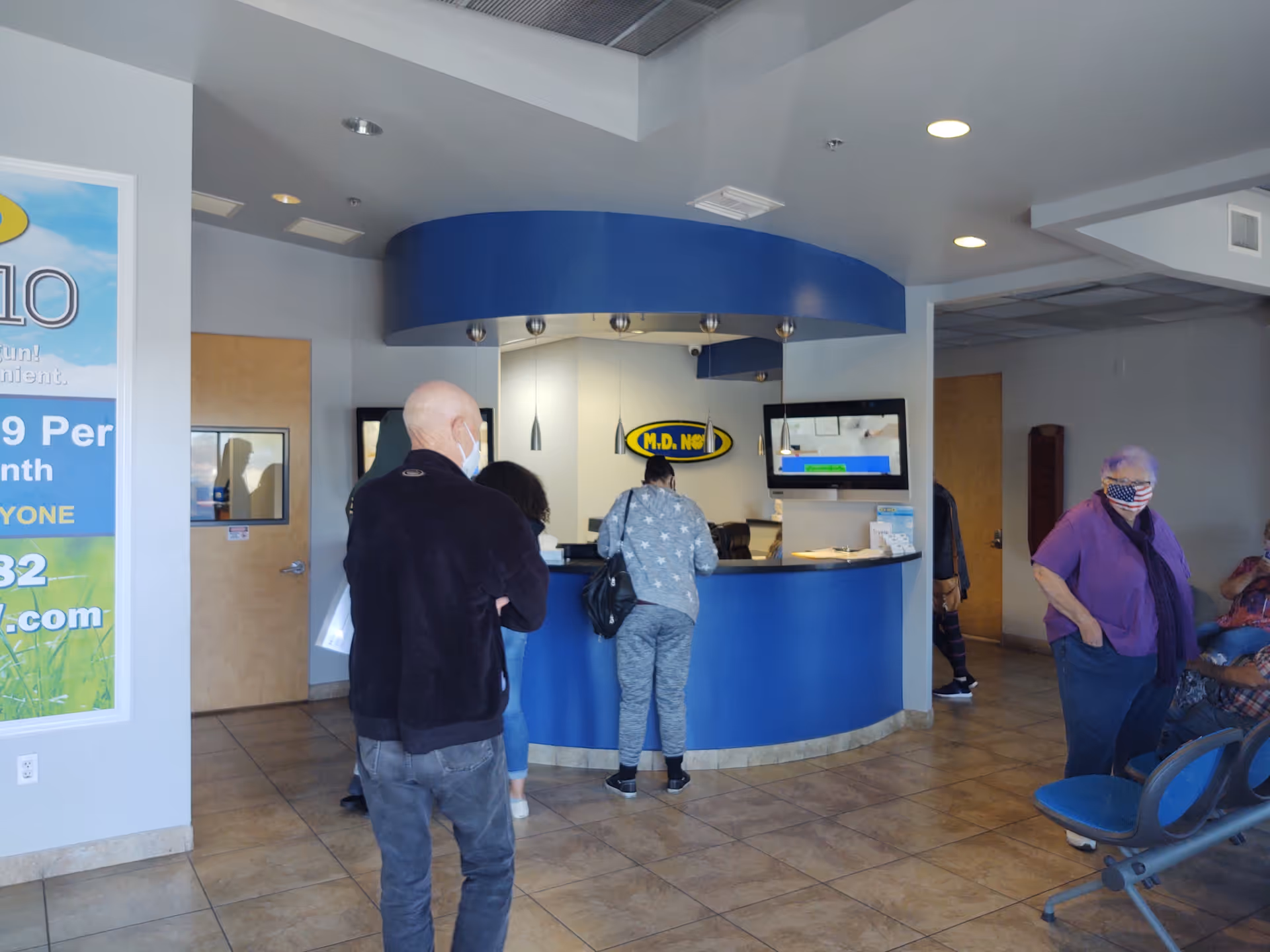 Residents and staff gather at a curved blue reception desk in a modern lobby.