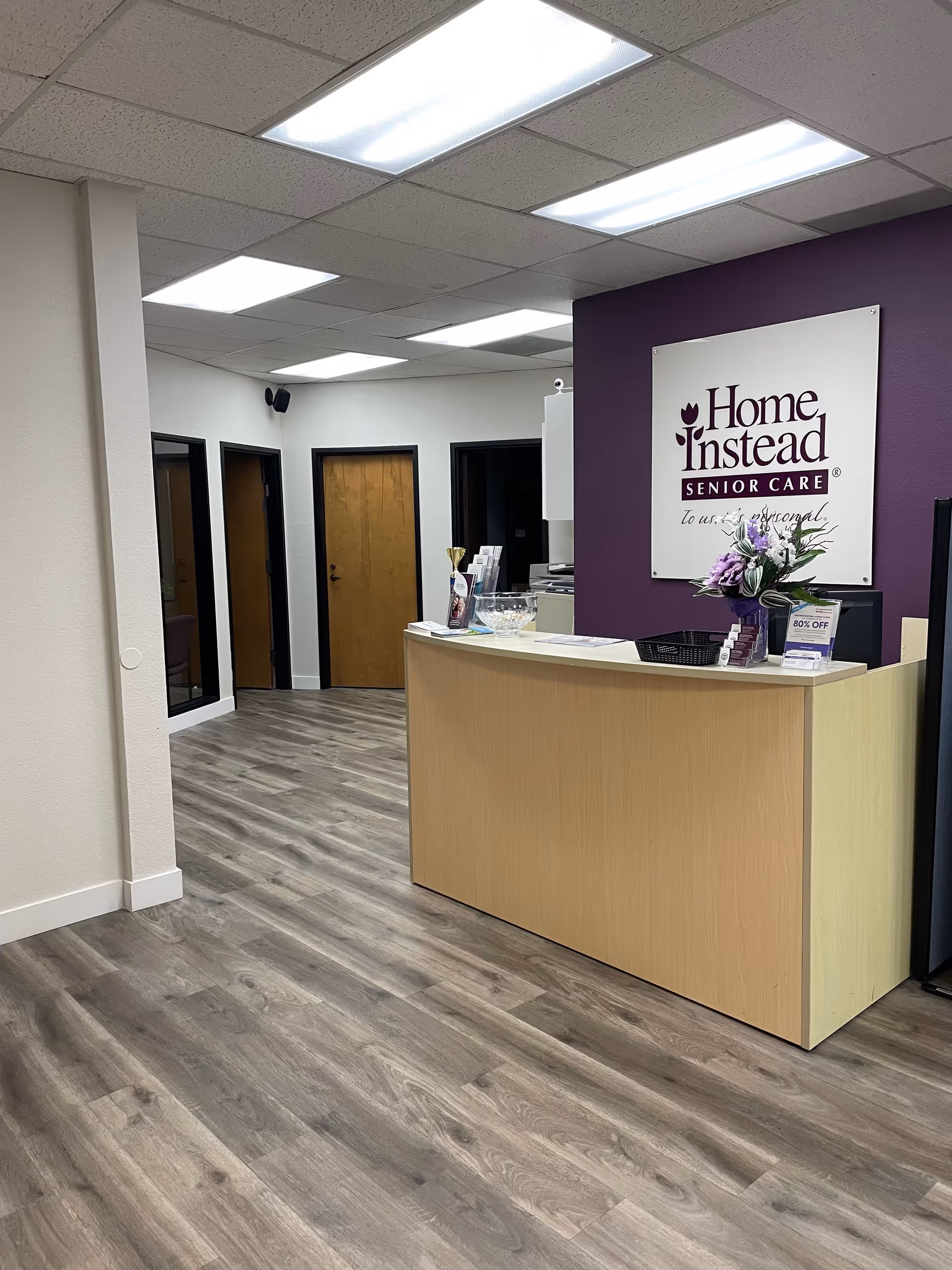 Reception desk with Home Instead sign in a purple-walled lobby.