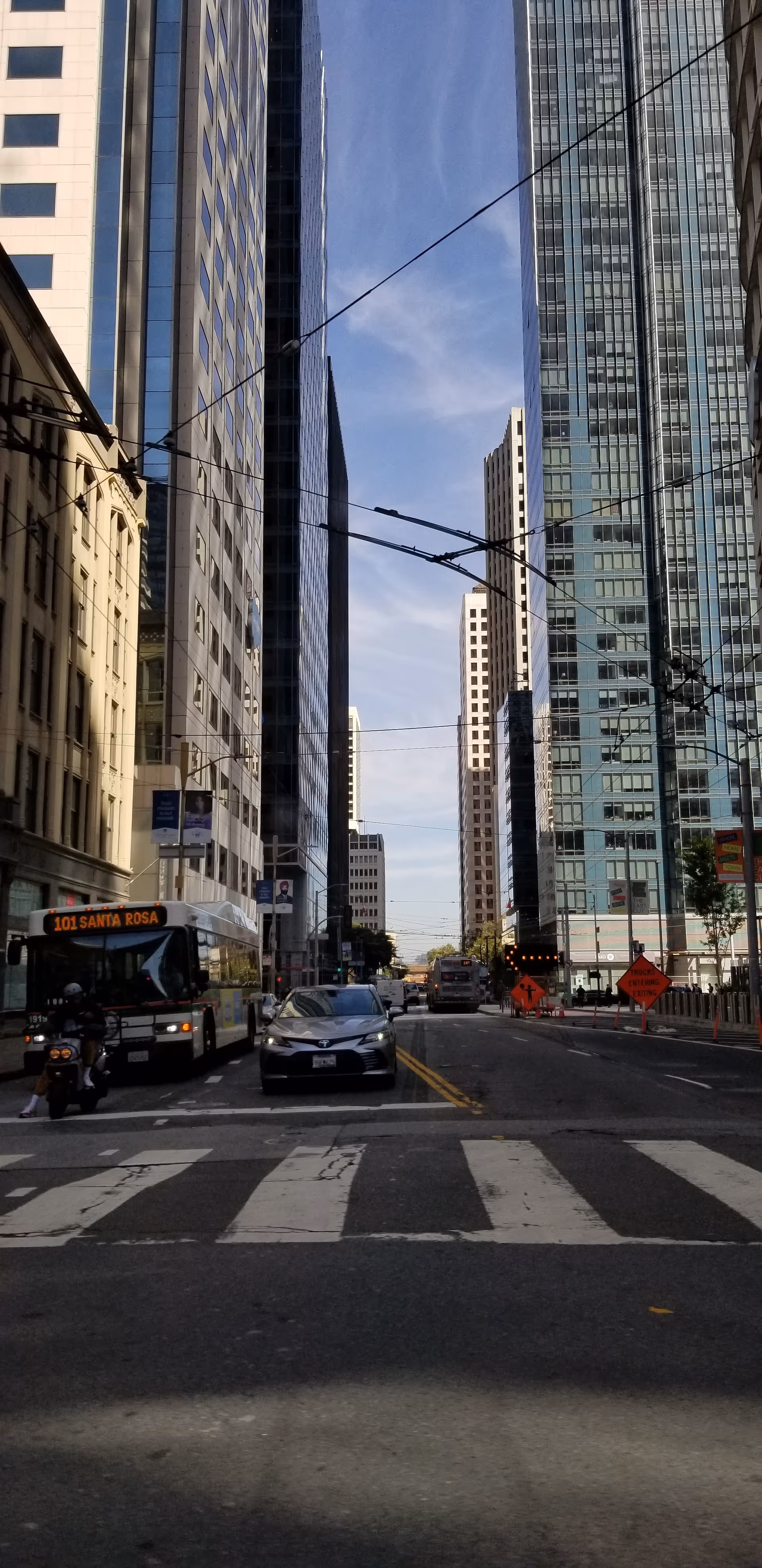 City street scene with tall buildings, traffic, and a crosswalk.