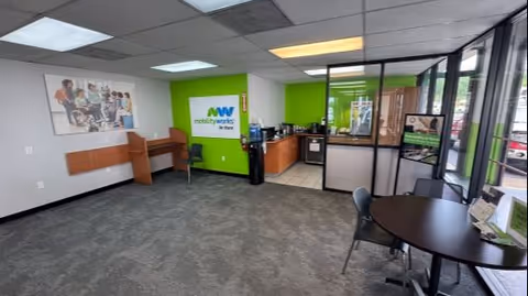 Interior MobilityWorks reception area with lime green wall, desks, and glass entry.