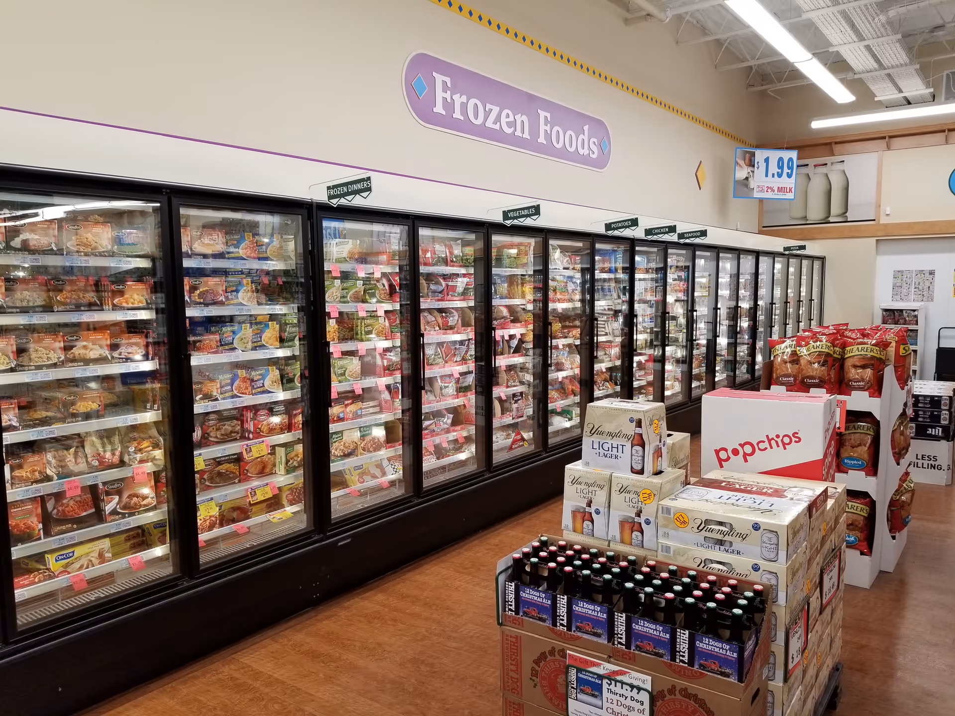 Inside Discount Drug Mart, long glass-door freezers display various frozen foods.