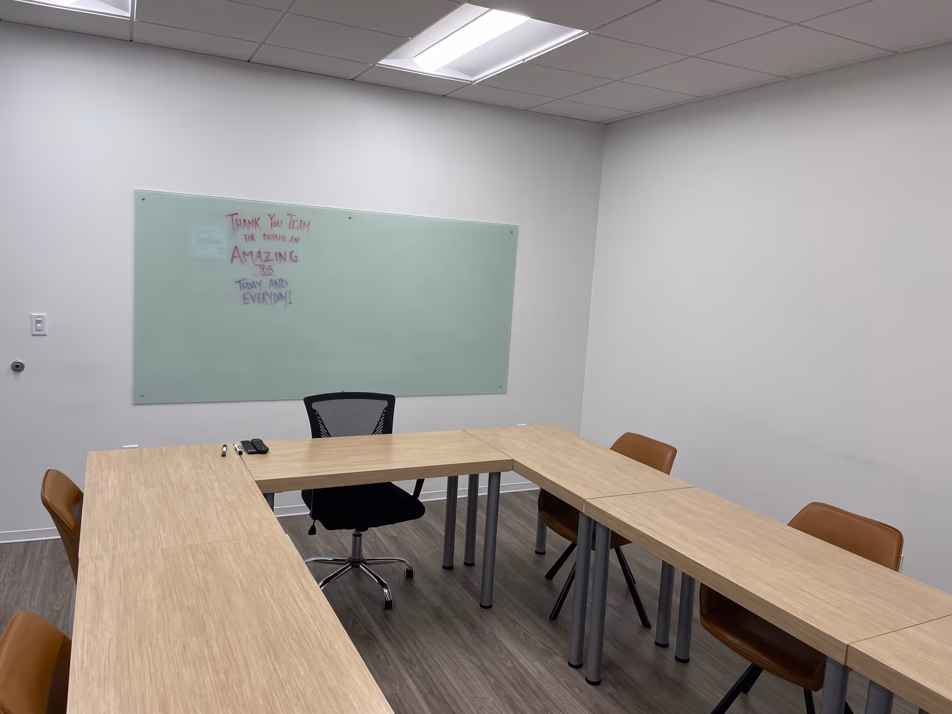 A conference-style meeting room with a U-shaped wooden table, chairs, and a whiteboard.