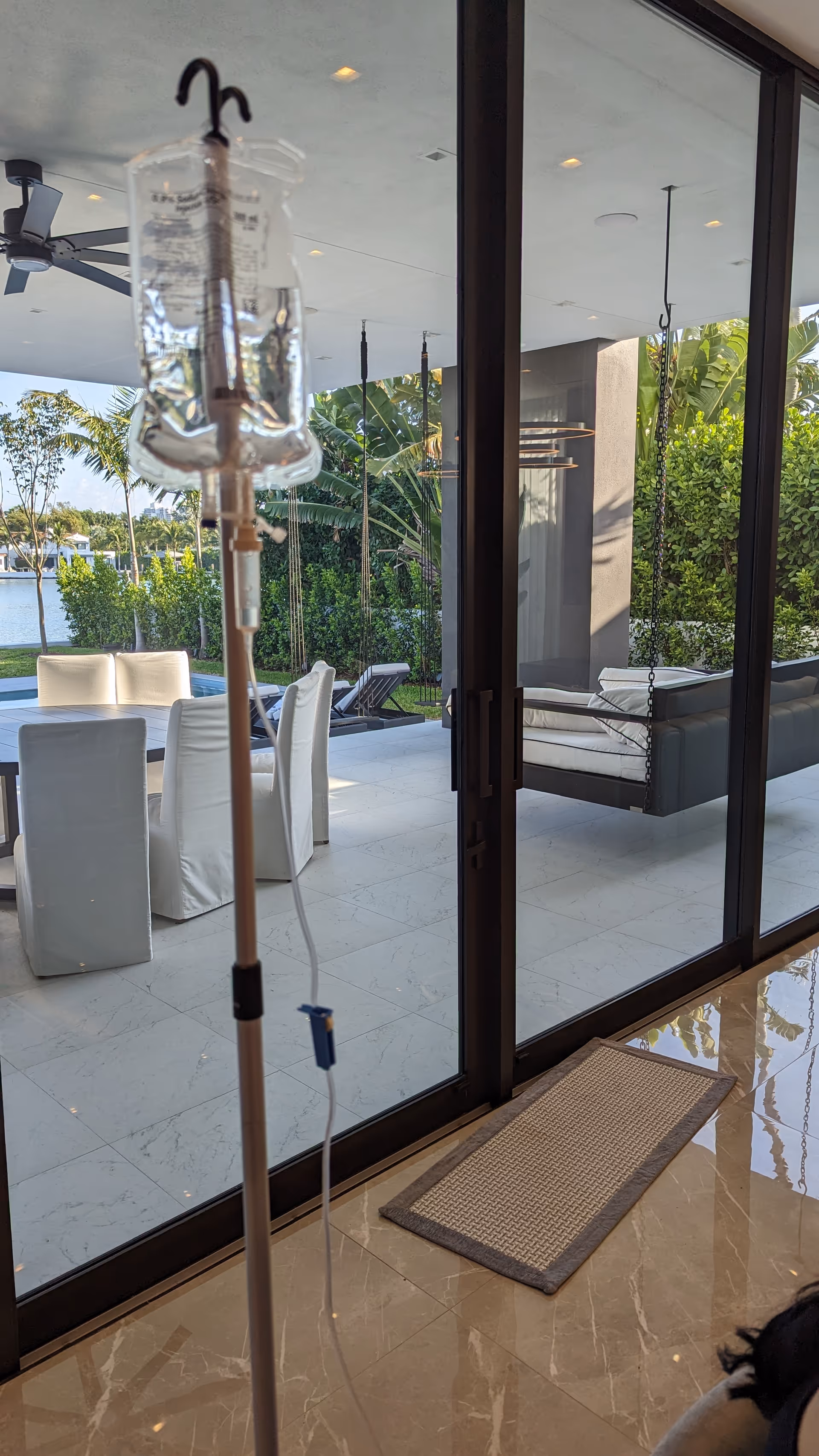 IV drip stand inside facility with glass doors opening to an outdoor patio.
