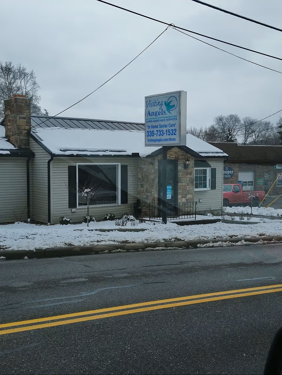 Exterior view of a Visiting Angels building with sign, snow on the ground.